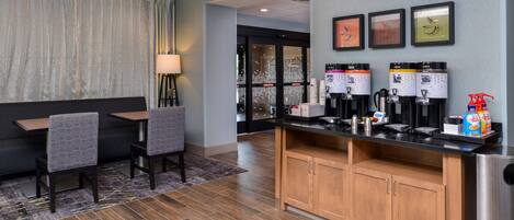 A hotel lobby with a seating area, a coffee station, and a reception desk.