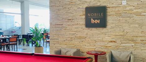 A billiards table in a room with a stone wall and a sign reading "NOBLE INN".