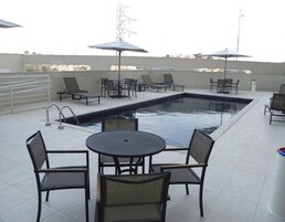 Uma área de piscina no terraço com espreguiçadeiras e guarda-sóis.