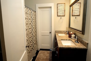 A bathroom with a shower curtain, a door, a sink, a mirror, and a towel. - Central Avenue Cottages (Memphis)