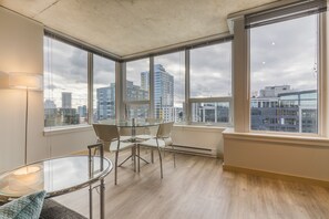 A modern room with large windows, a glass table, and a chair. - Domicile Suites At Verve (Seattle)