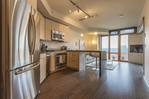 A modern kitchen with stainless steel appliances, wooden cabinets, and a large island. - Domicile Suites At Verve (Seattle)
