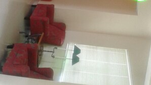 Un vestíbulo de hotel con una escalera, una zona de estar y un reloj en la pared.