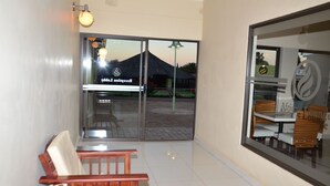 Un área de recepción con puerta de vidrio que da al exterior, un banco e iluminación en la pared.