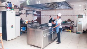 Una cocina comercial con electrodomésticos de acero inoxidable, una estufa grande y ventilación por encima.