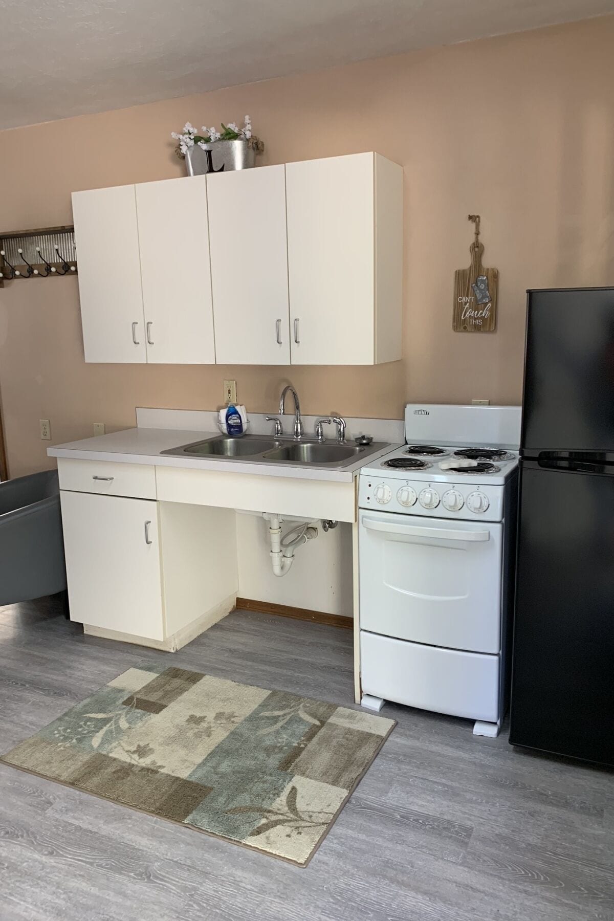 A kitchen with white cabinets, a double sink, a stove, and a refrigerator.