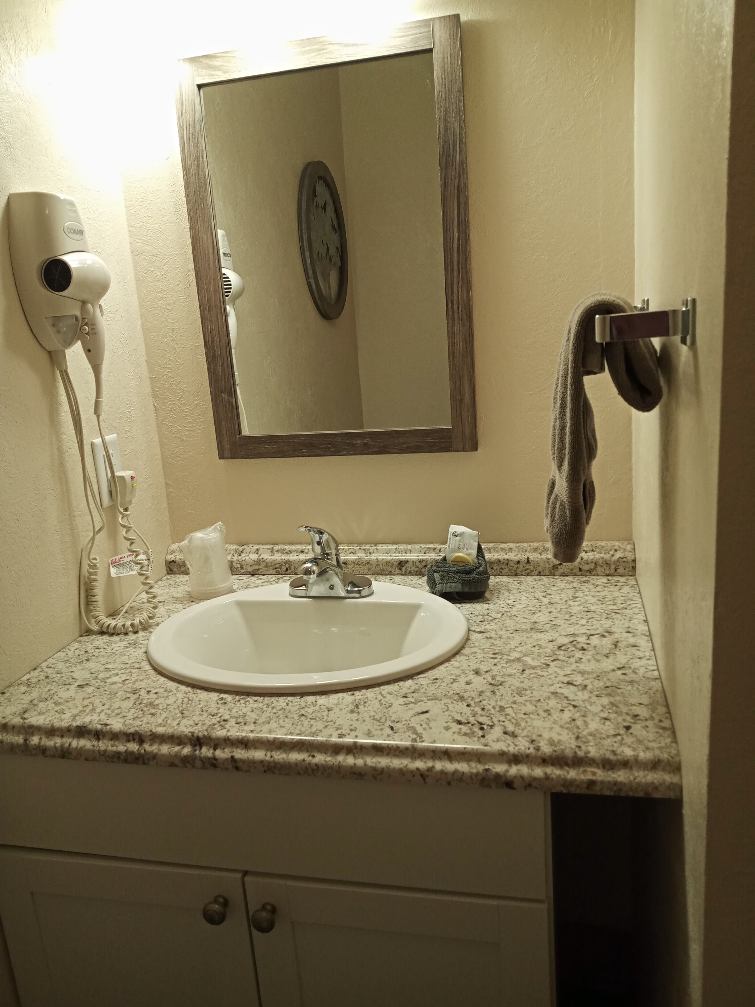 A bathroom with a sink, a hairdryer, a mirror, and a towel rack.