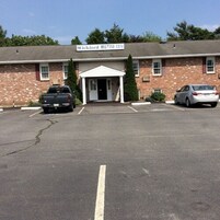 Un edificio con un cartel que dice "Wickiord Motor Inn" y un estacionamiento con dos coches.