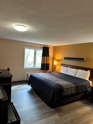 A hotel room with a bed, a desk, a lamp, and a window with curtains. - Wickford Motor Inn (North Kingstown)