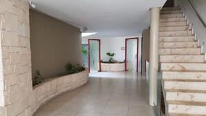 A spacious hallway with a curved wall, a staircase, and a door marked with the number 104. - In heart of town 1BR condo in steps distance from the 5th Av by Happy Address (Playa del Carmen)