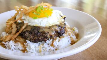 A plate of food with rice, a fried egg, and a piece of meat topped with fried onions.