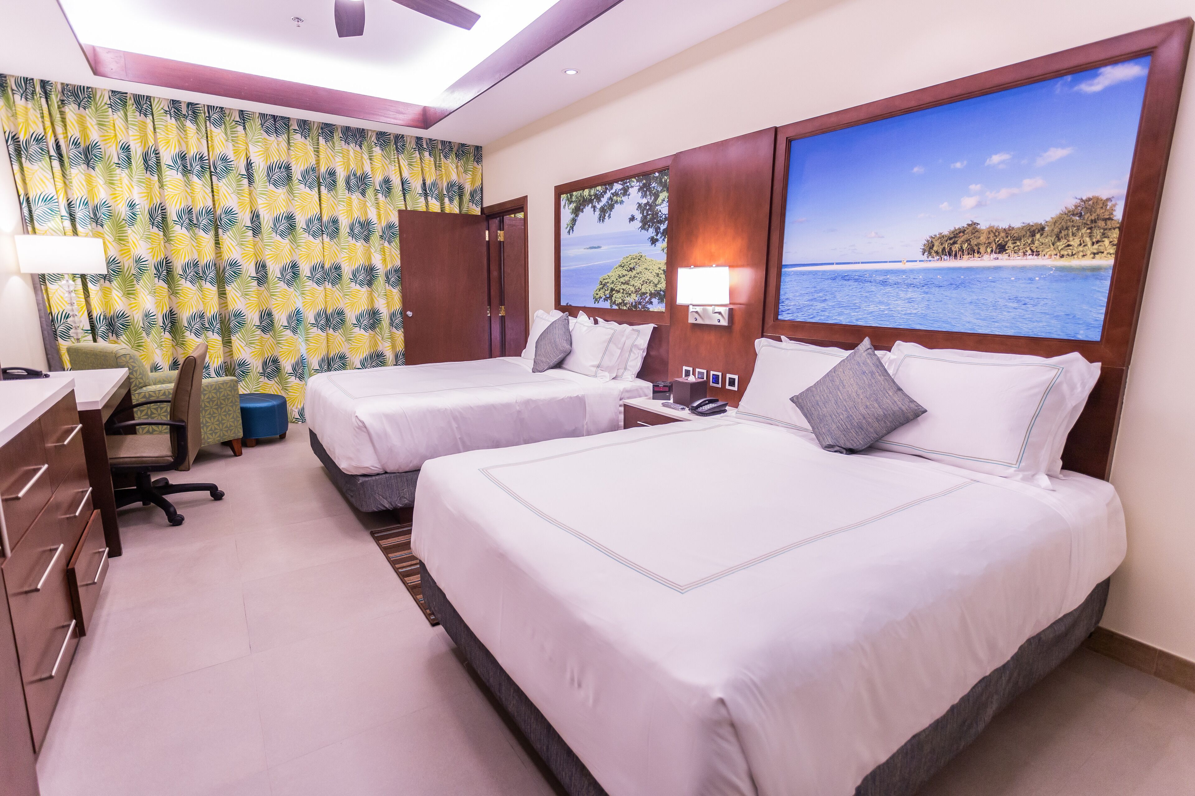 A hotel room with two beds, a desk, and a chair.