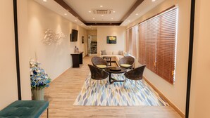 A hallway with a sofa, chairs, a table, and a decorative plant. - Surfrider Resort Hotel (Saipan)
