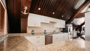 A modern kitchen with granite countertops, white cabinetry, and stainless steel appliances. - Surfrider Resort Hotel (Saipan)