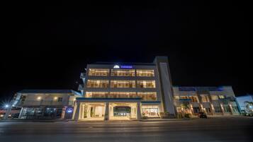 Un hotel de varios pisos con un llamativo letrero 'SURFRIDER', una entrada cubierta y un área de estacionamiento.