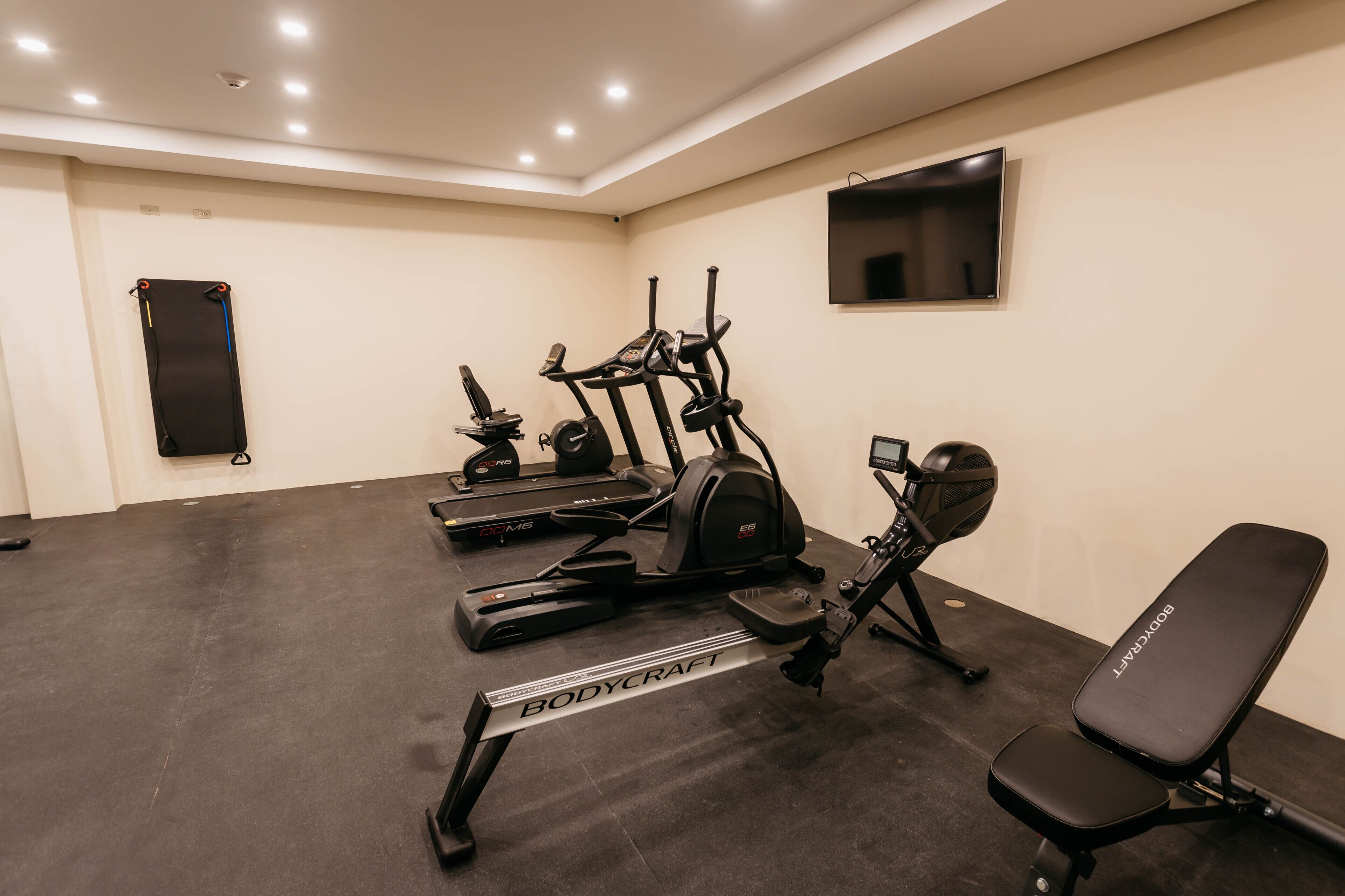 A gym with treadmills, an elliptical, a bench, and a punching bag.