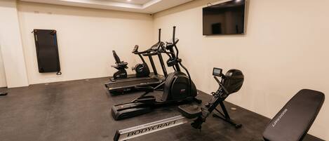 A gym with treadmills, an elliptical, a bench, and a punching bag.
