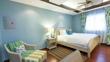 A hotel room with a bed, a chair, a nightstand, and a ceiling fan.