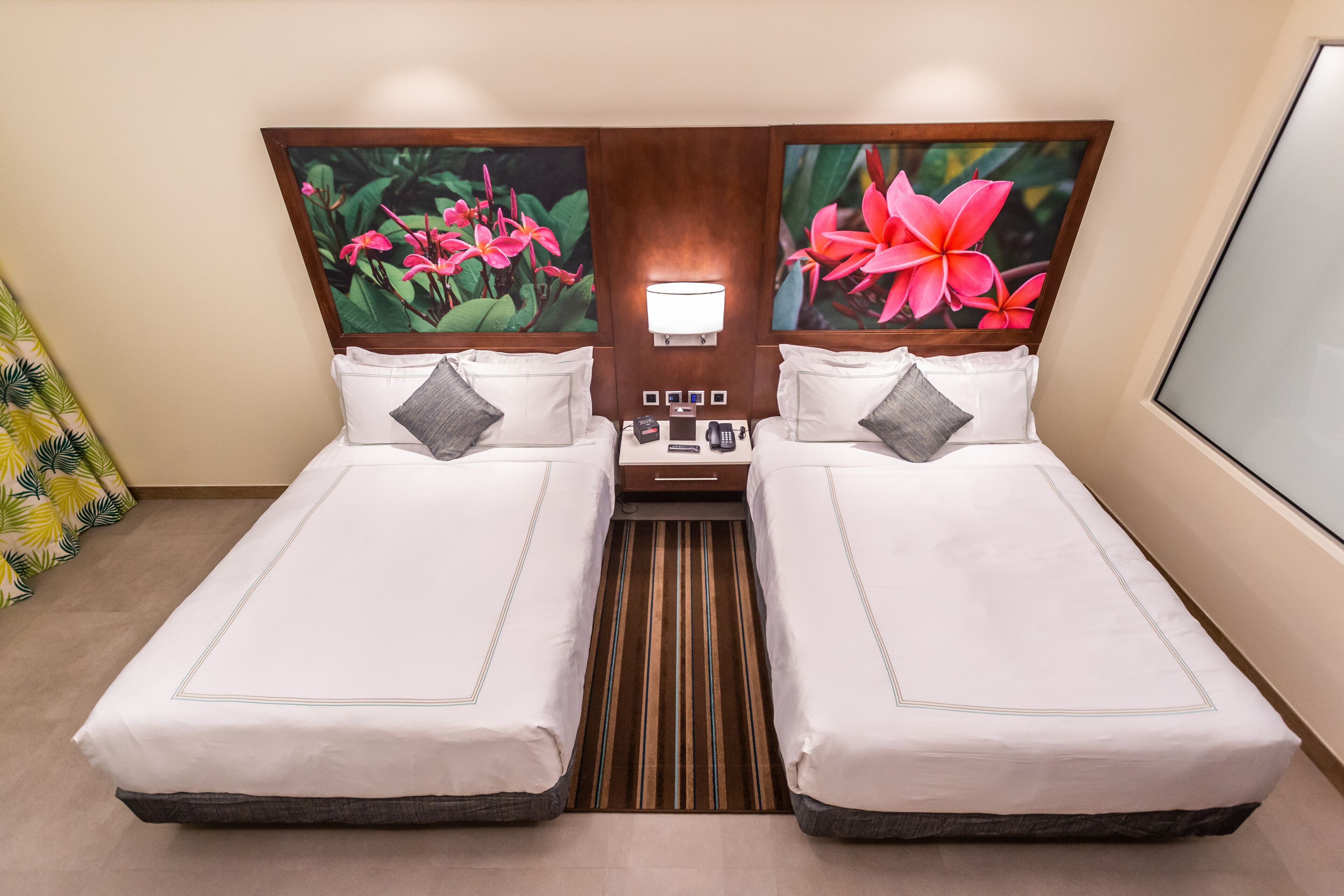 A double bed room with two nightstands, a wall-mounted lamp, and two framed floral pictures.
