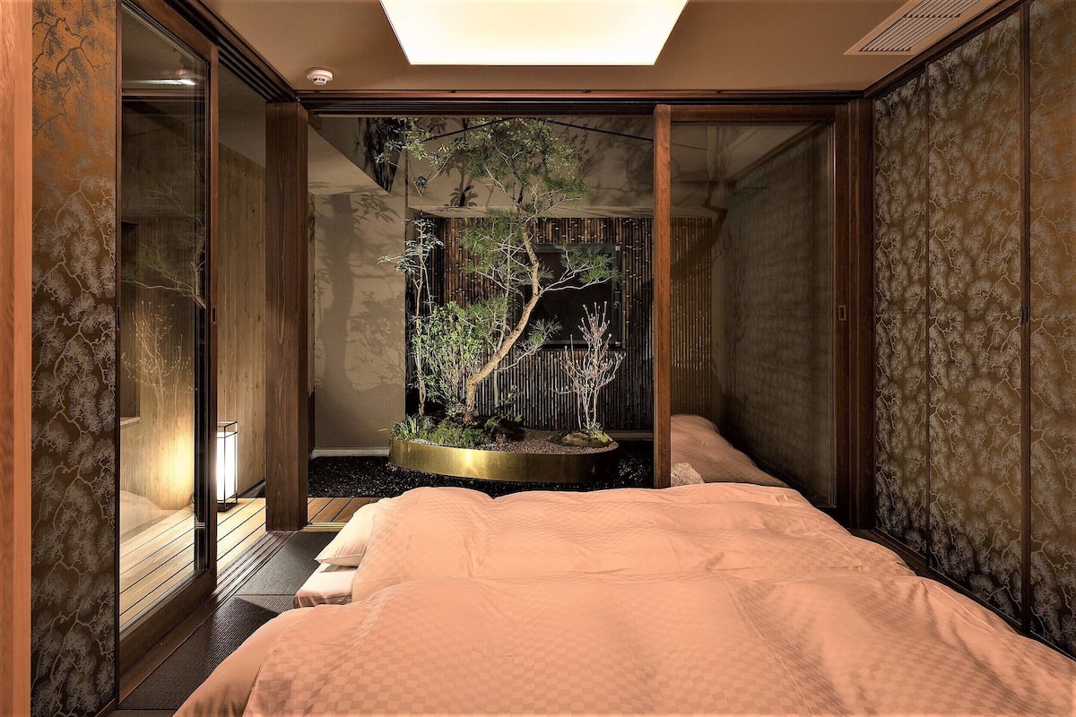 A room with a bed, a small indoor garden, and a sliding door.