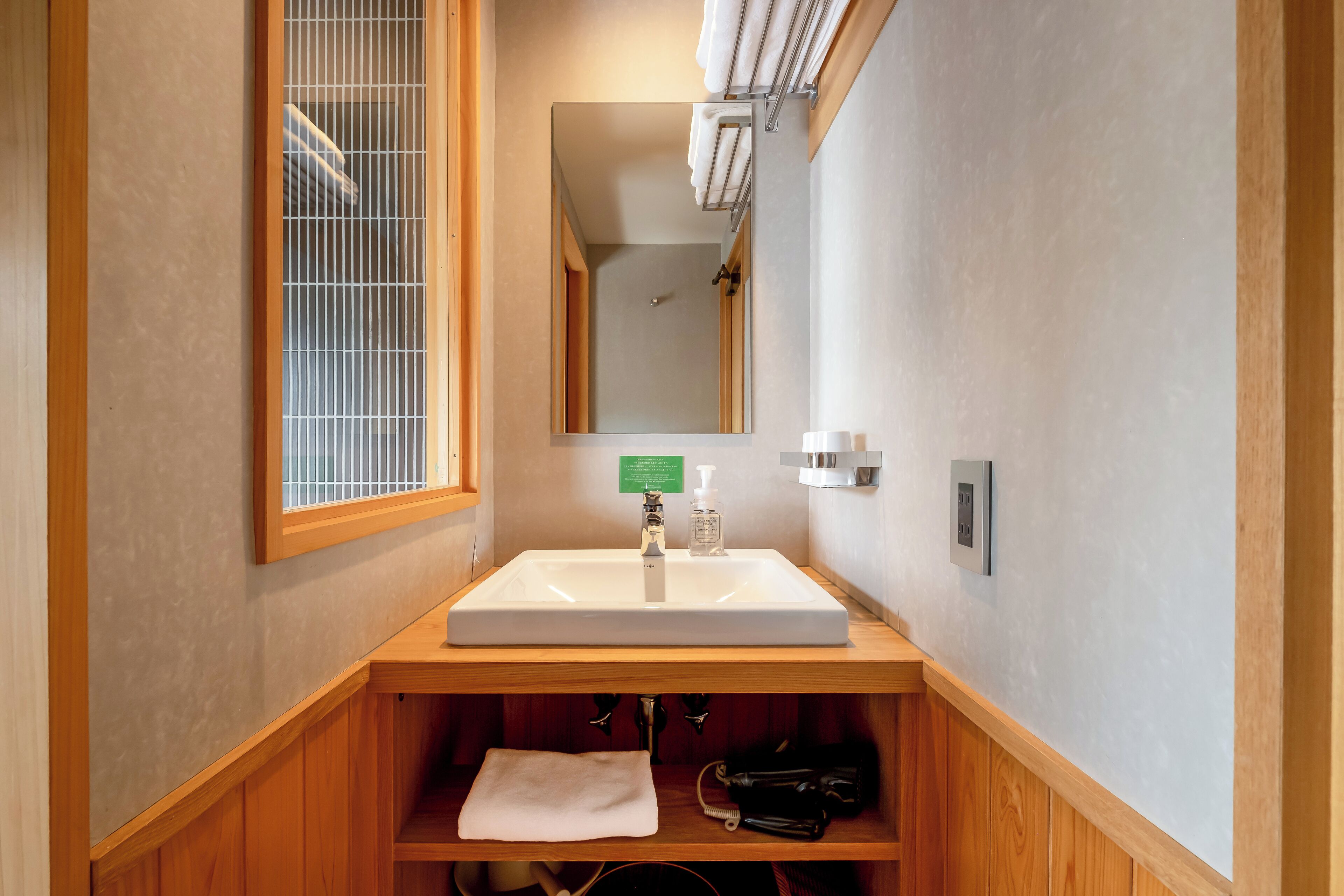 Un baño con tocador de madera, un espejo grande y una ventana con vistas.