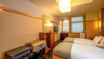 Una habitación de hotel con dos camas, un escritorio con una computadora, un televisor y una maleta.