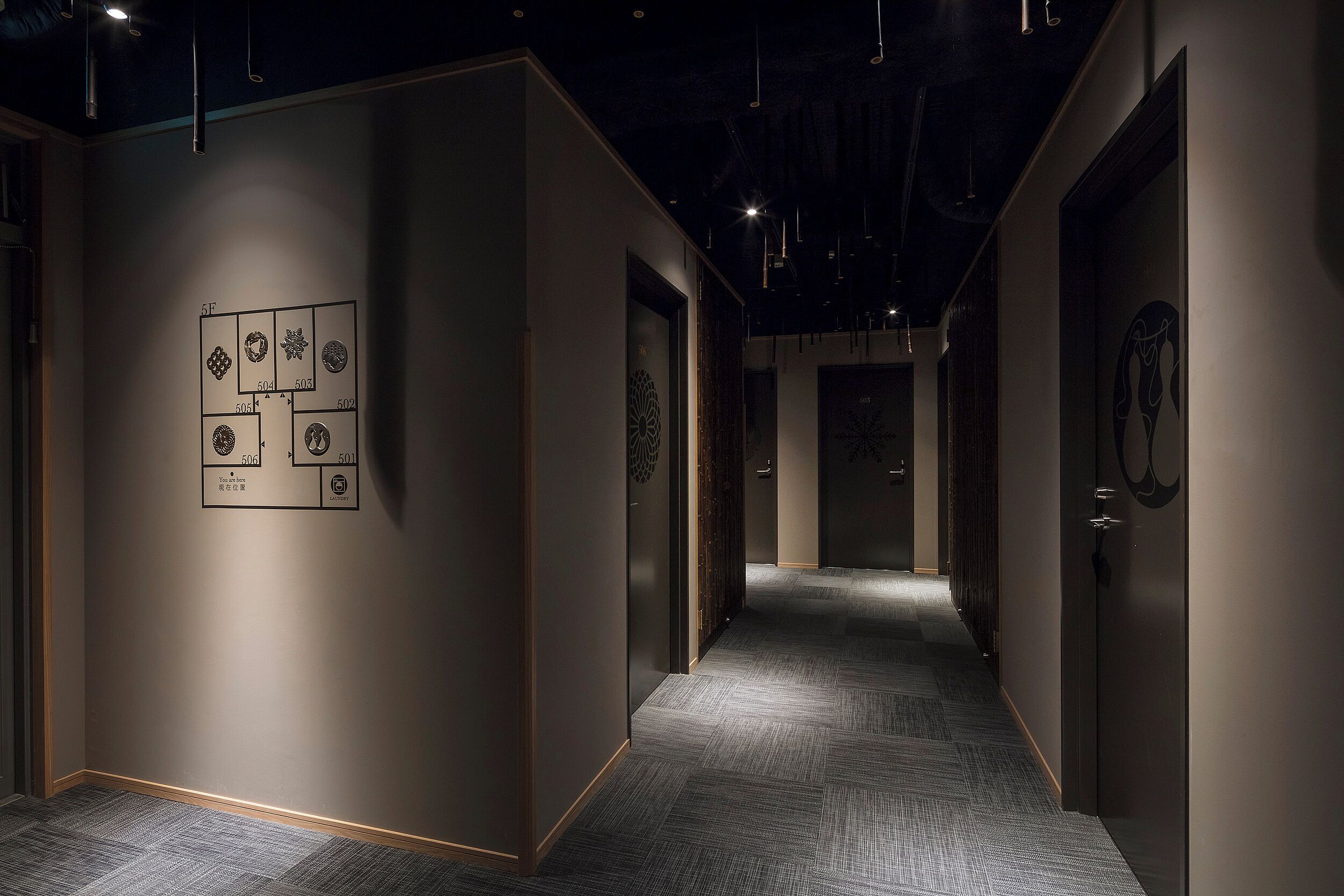 A hallway with a carpeted floor and walls adorned with framed artwork.