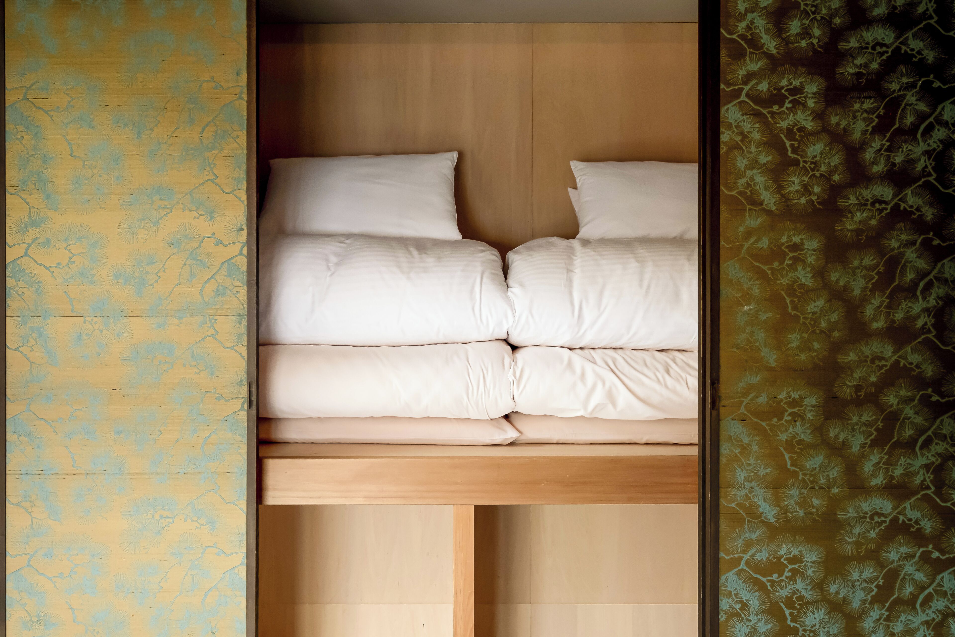 A bed with white bedding in a room with wooden headboard and walls.