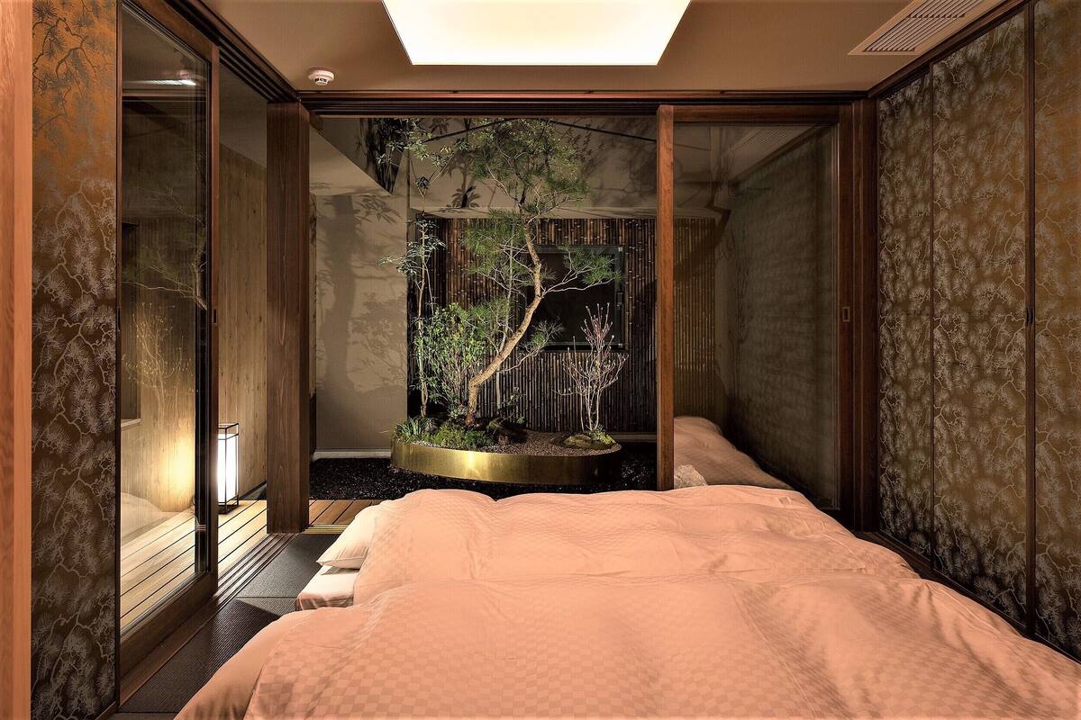 A room with a bed, a small indoor garden, and a sliding door.
