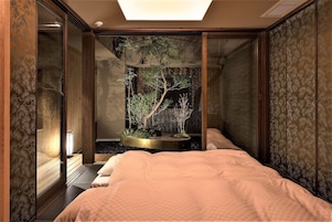 Una habitación con cama, un pequeño jardín interior y una puerta corredera.