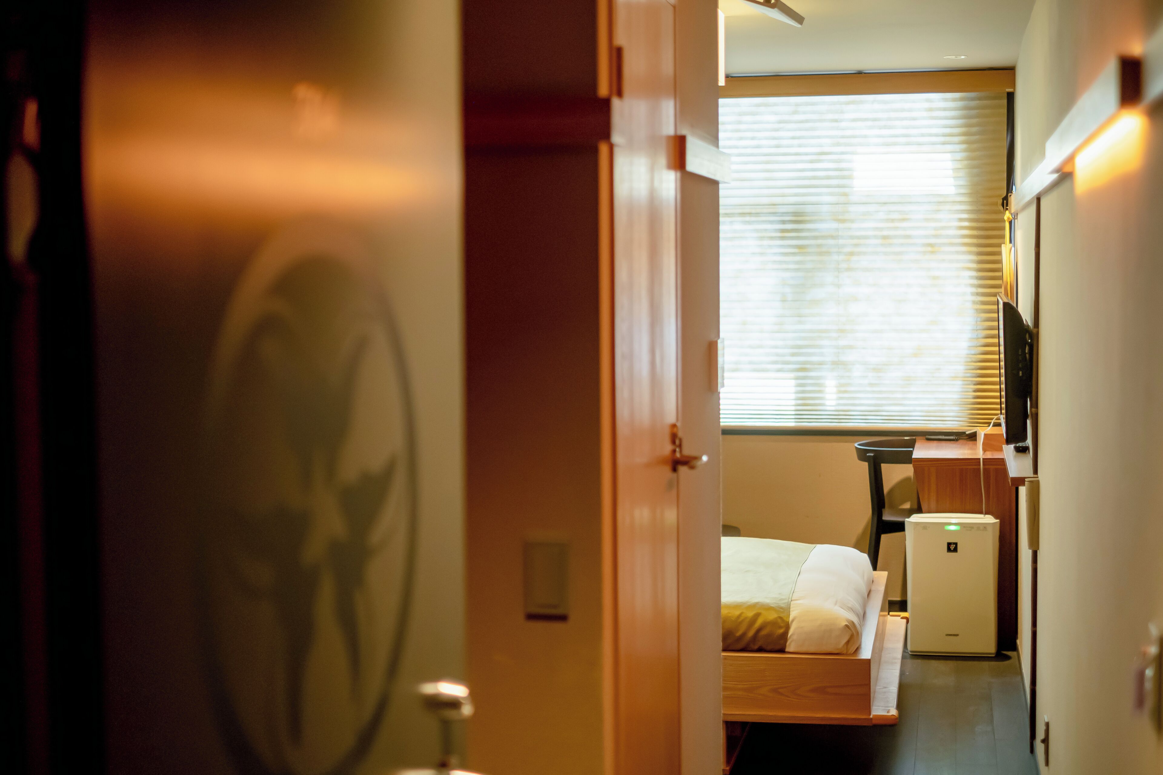 A hotel room with a bed, a desk, a chair, a TV, and a small refrigerator.