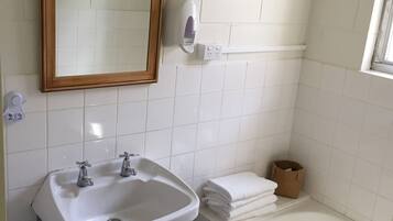 Un baño con un lavamanos blanco, un espejo y una bañera blanca.