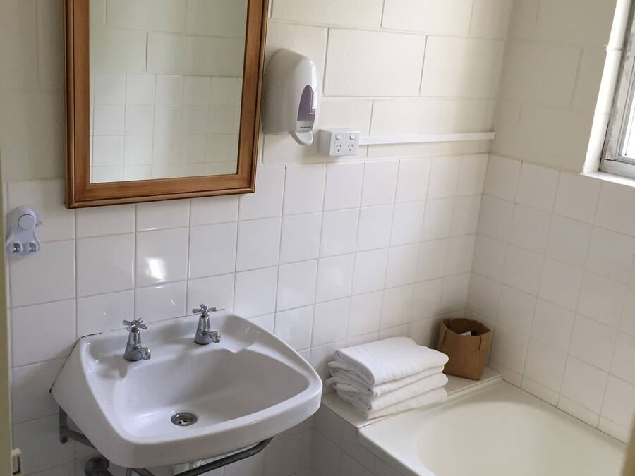 Un baño con un lavamanos blanco, un espejo y una bañera blanca.