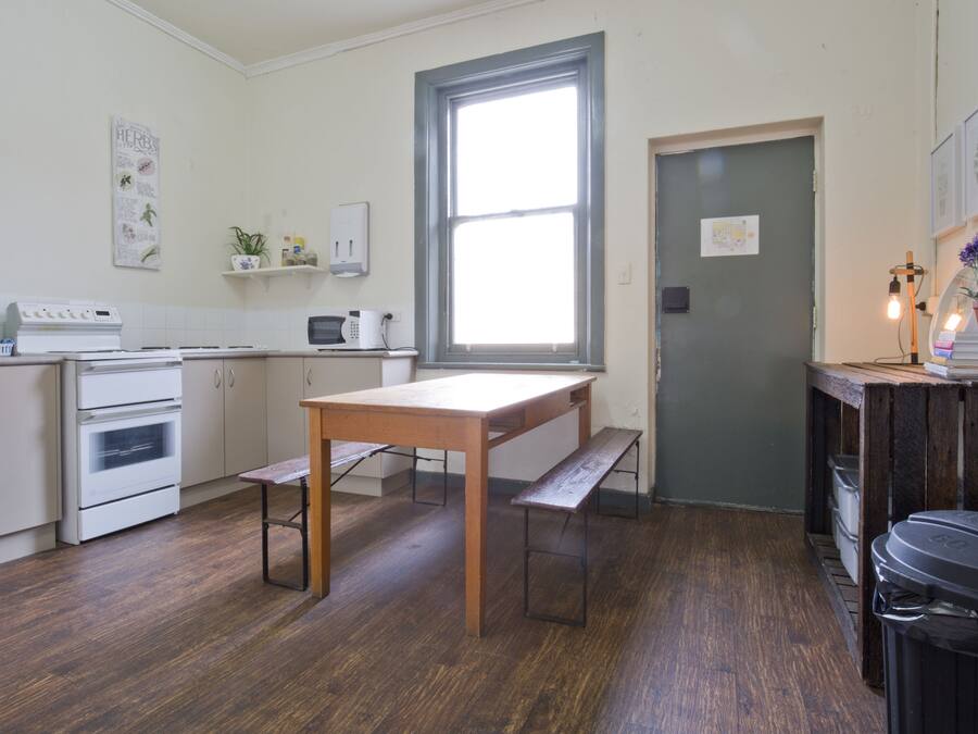 Una cocina compacta con electrodomésticos blancos, una mesa de madera y un banco.