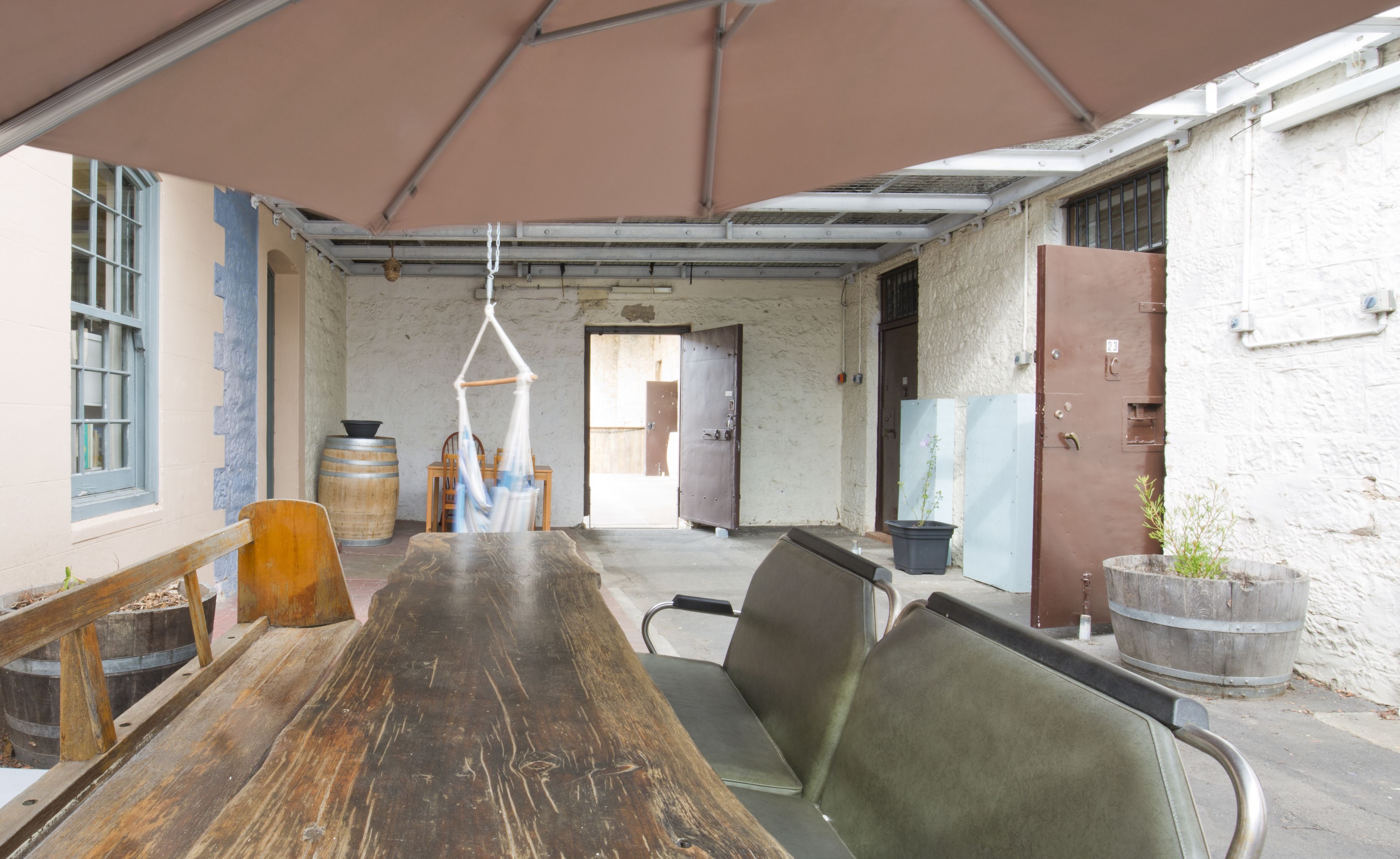 A long wooden table with metal chairs, a hanging light fixture, and a large window with blue shutters.