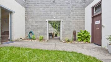 A courtyard with a concrete wall, a door labeled "SHOWERS," and a small garden area with plants and a bench.