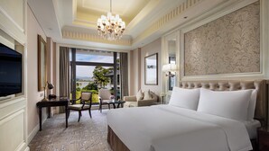 Une chambre d’hôtel spacieuse, dotée d’un grand lit, d’une télévision, d’un bureau avec une chaise et offrant une vue sur l’extérieur.