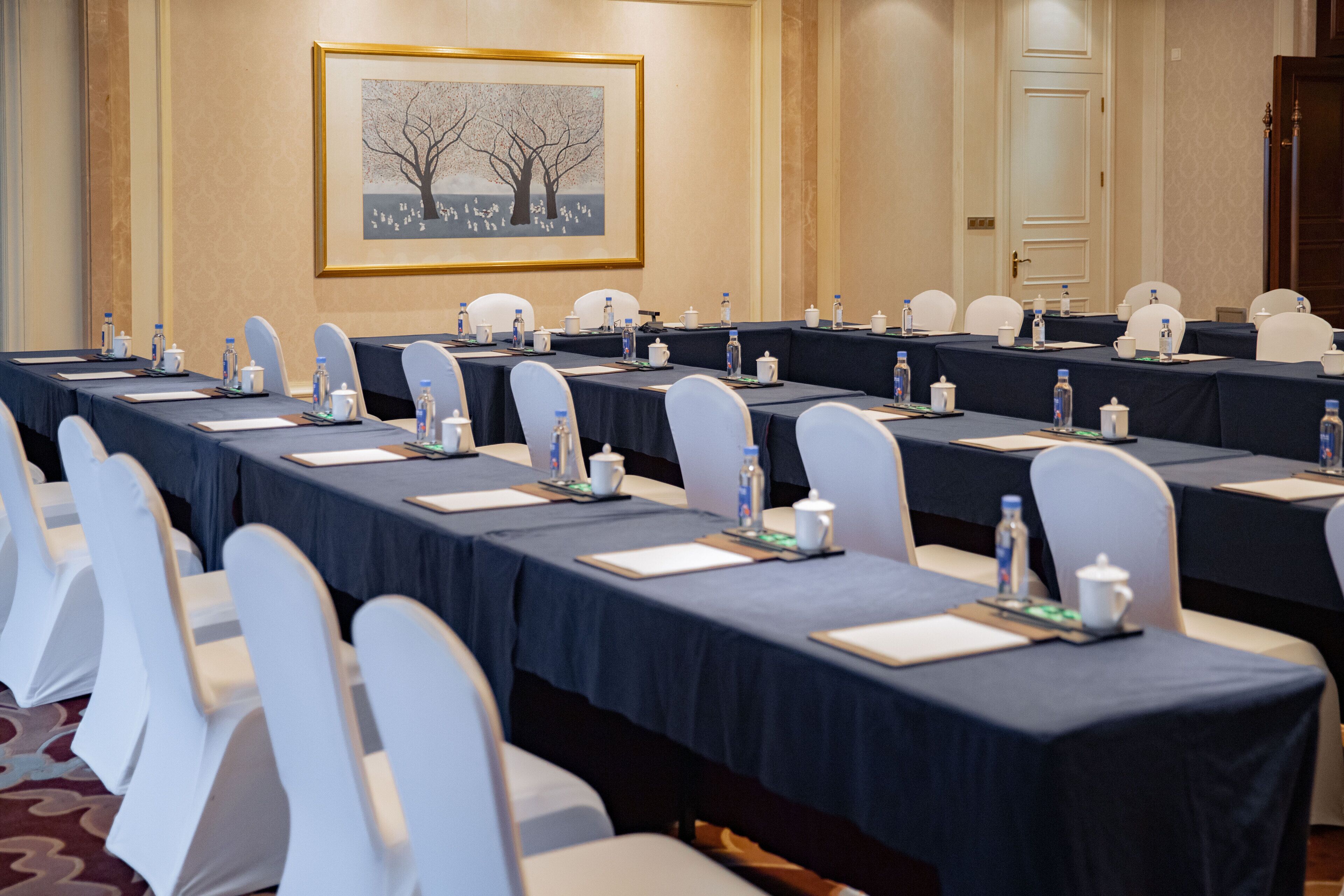A conference room with multiple tables, chairs, and water bottles.