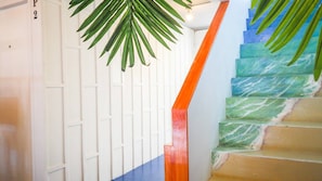 Un escalier avec une rampe en bois et un décor composé de motifs de feuilles de palmier.