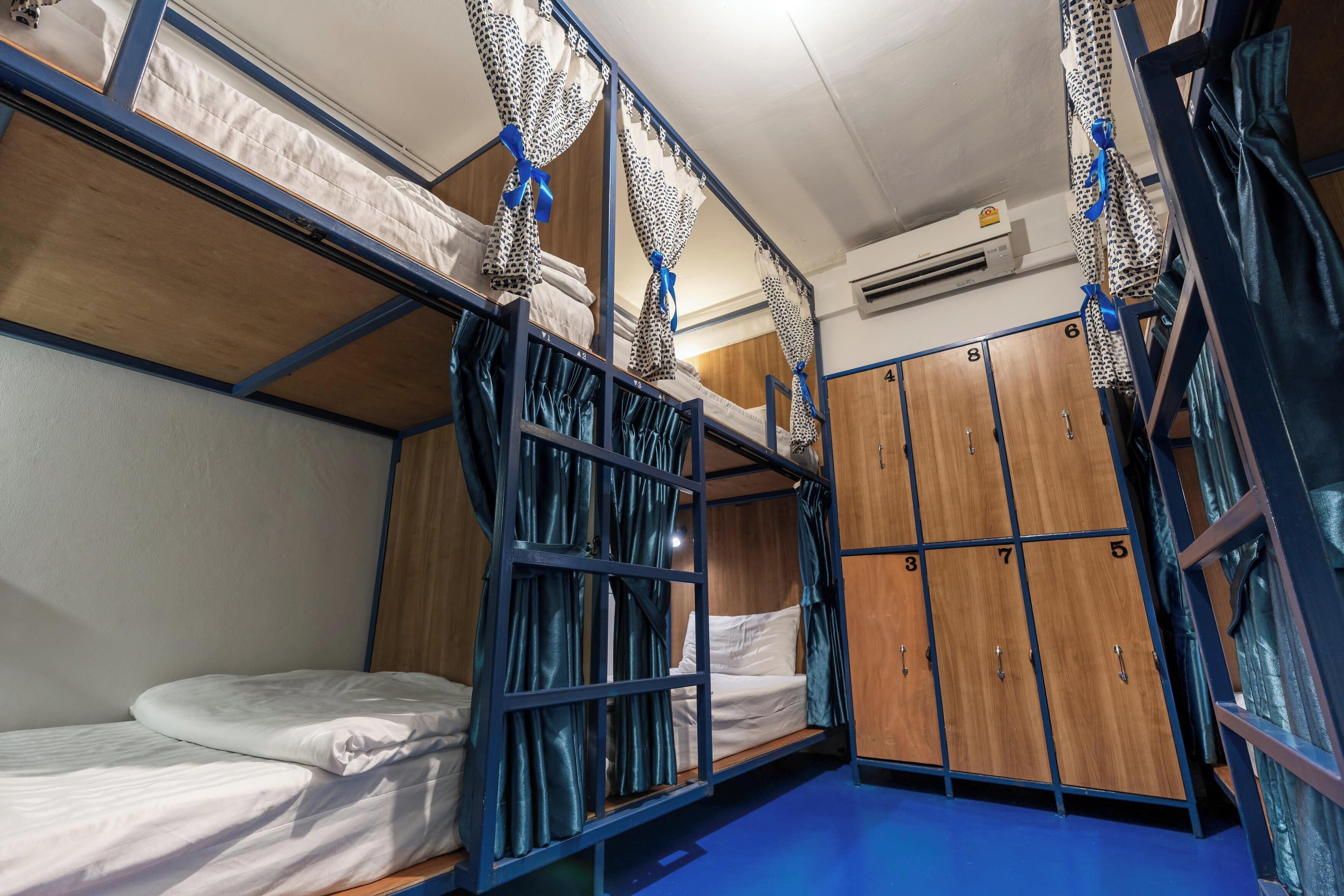 Ein Schlafsaalzimmer mit Etagenbetten, einem Kleiderschrank und einem blauen Boden.
