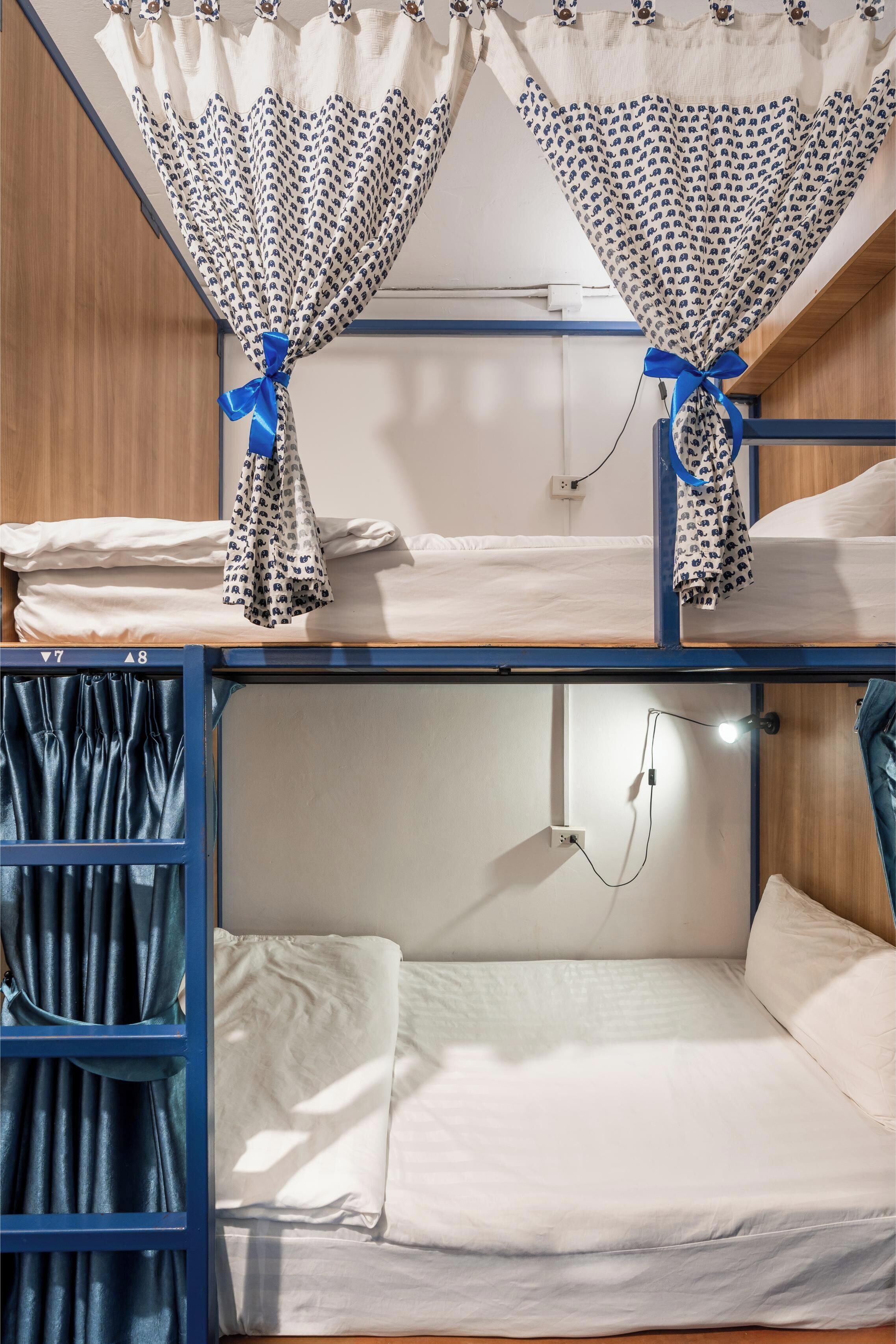 A bunk bed room with two beds, a wardrobe, and curtains.
