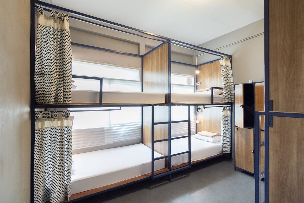 Habitación con literas de madera, un escritorio pequeño y un armario.