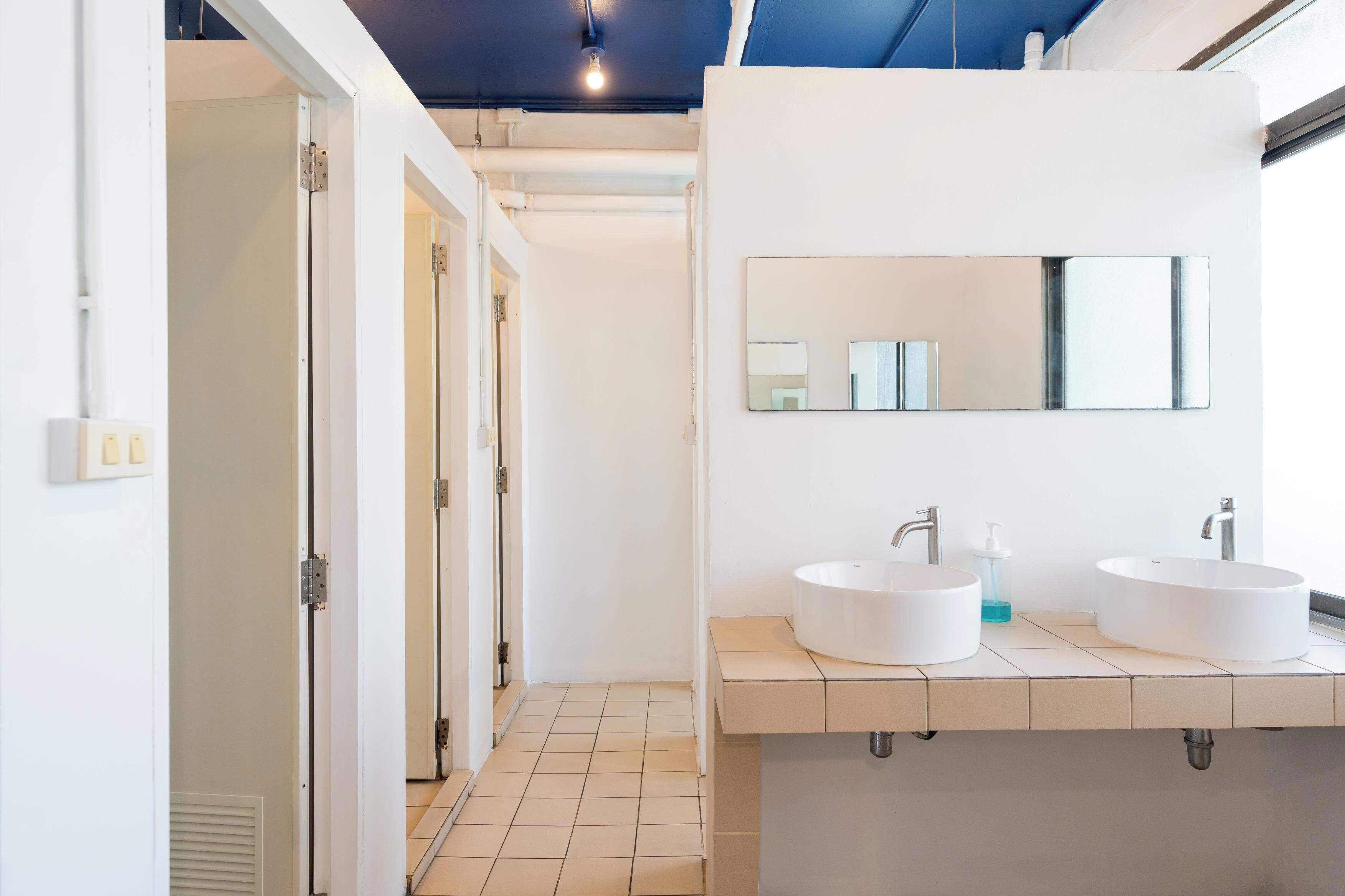 A modern bathroom with two sinks, a large mirror, and a walk-in shower.