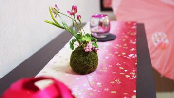 A delicate vase sits atop a table, surrounded by a soft floral tablecloth.