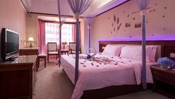 Une chambre d’hôtel avec un lit à baldaquin, une télévision, un bureau et une chaise.