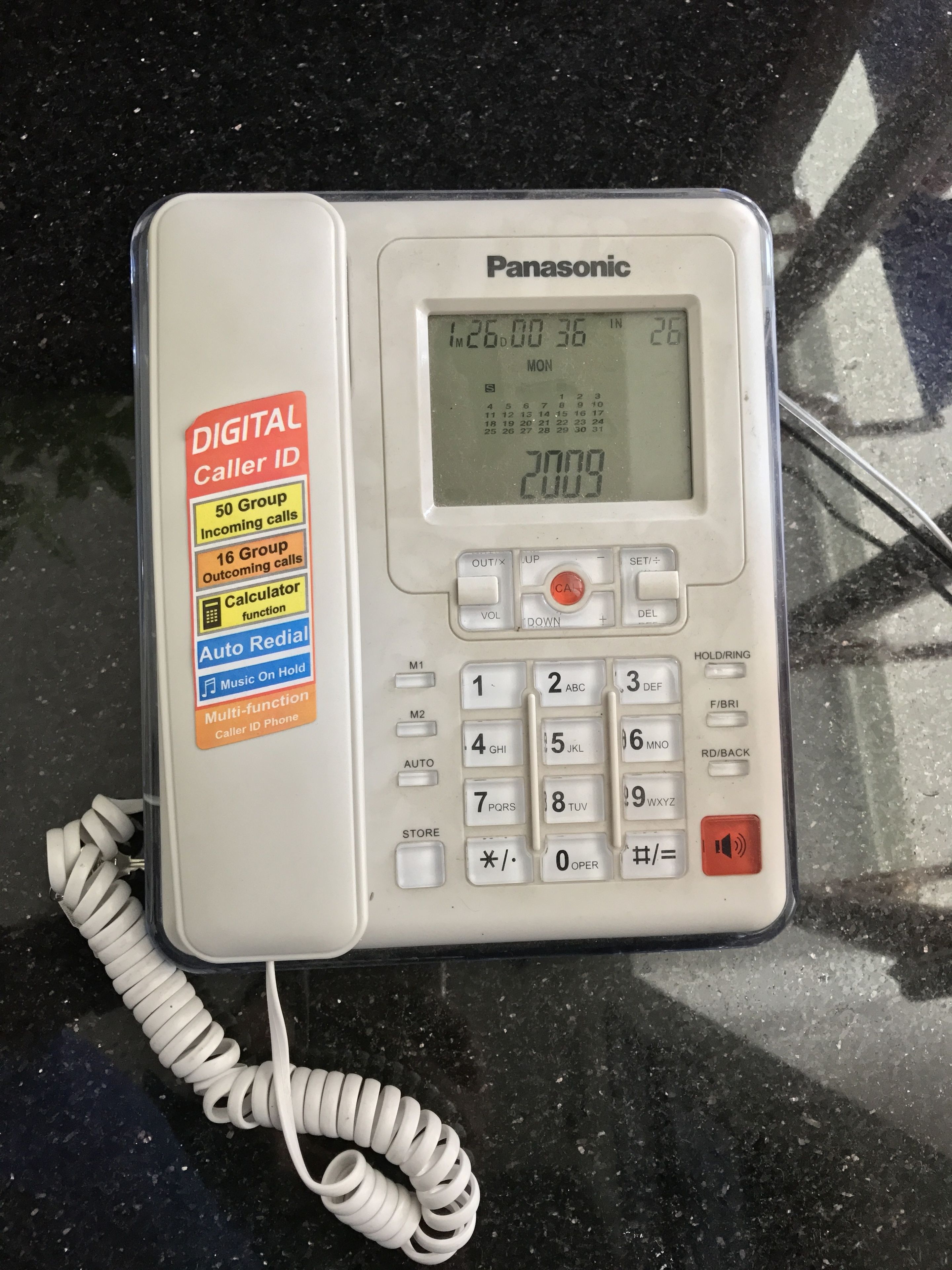 A Panasonic digital phone with a coiled cord, a display screen, and a keypad.