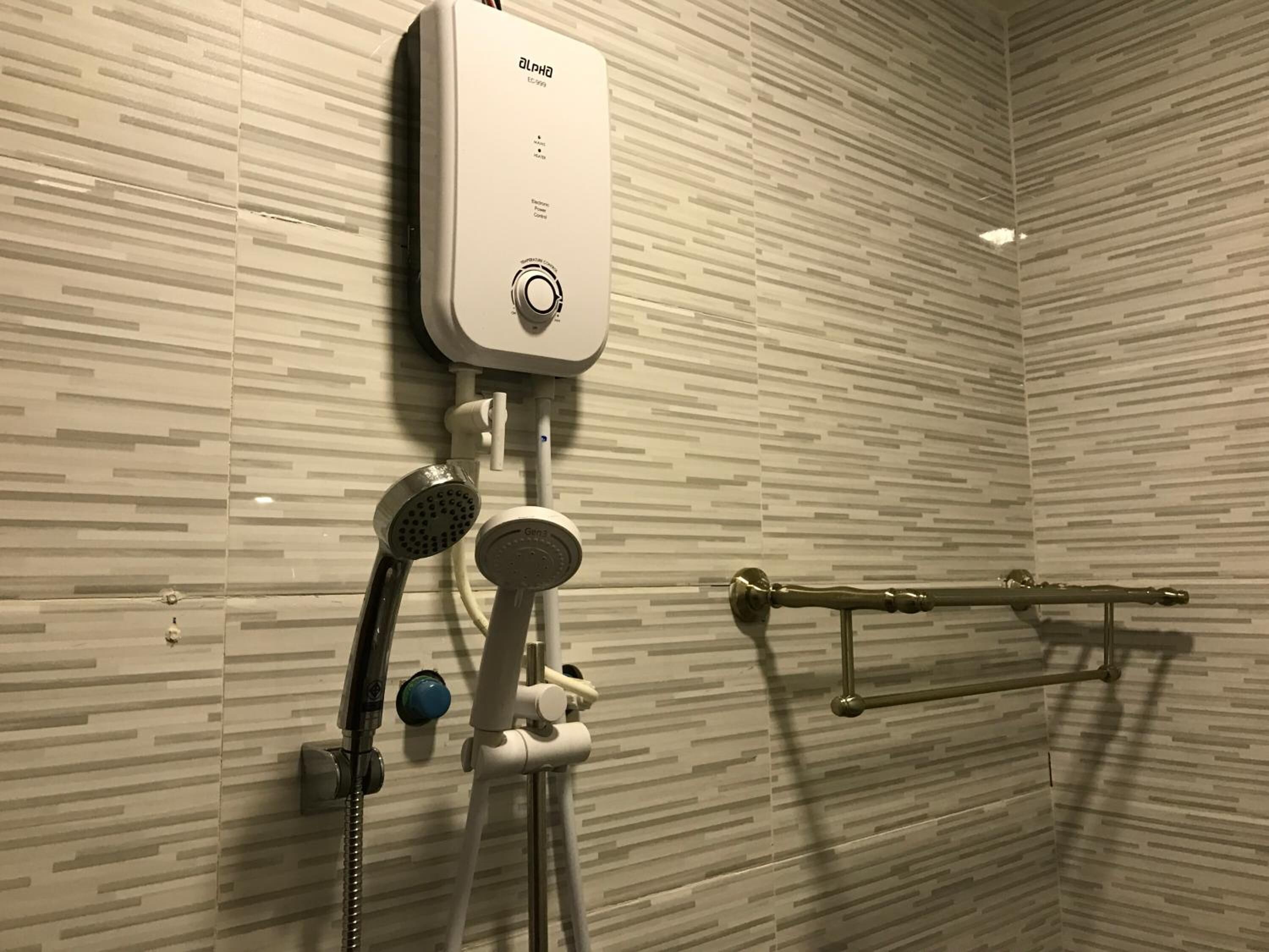 A modern bathroom with a wall-mounted electric shower, a handheld showerhead, and a towel rack.