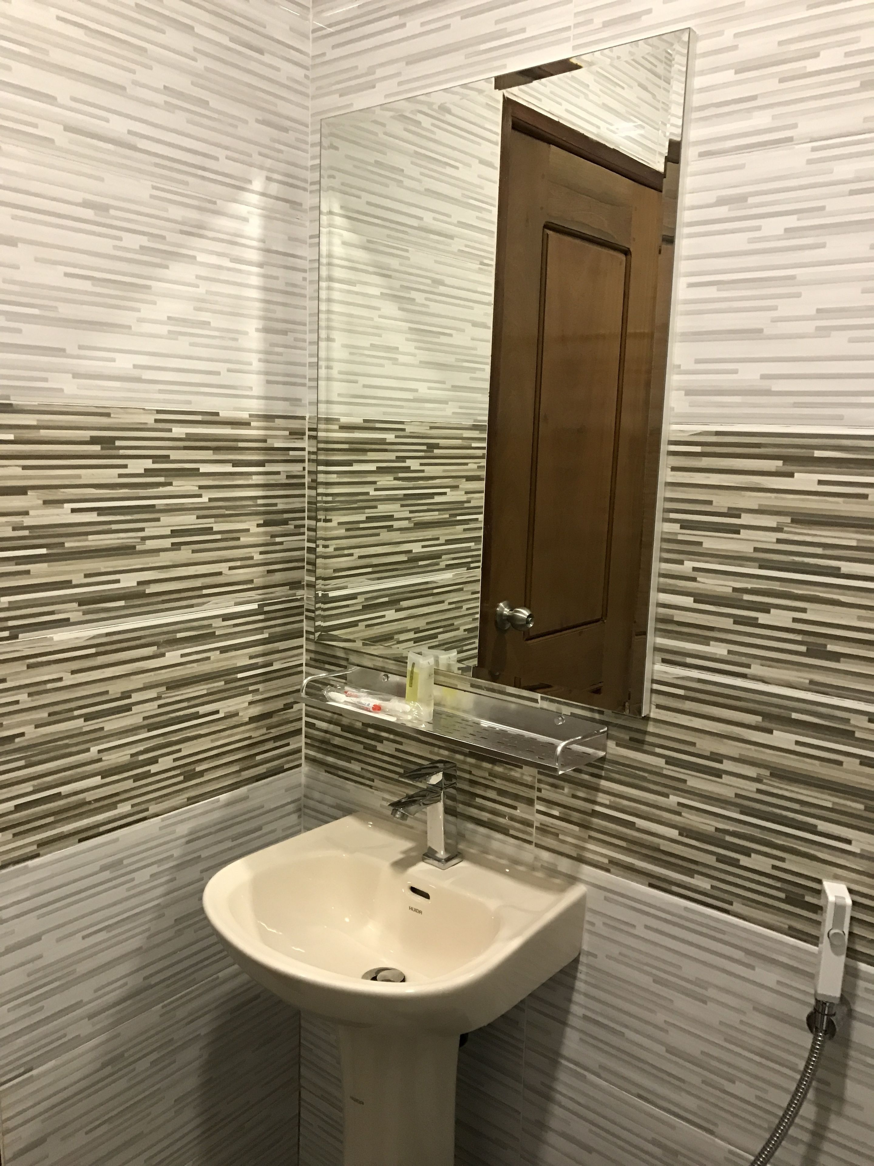 Baño de diseño moderno, con cabina de ducha de vidrio, lavamanos blanco y puerta de madera.
