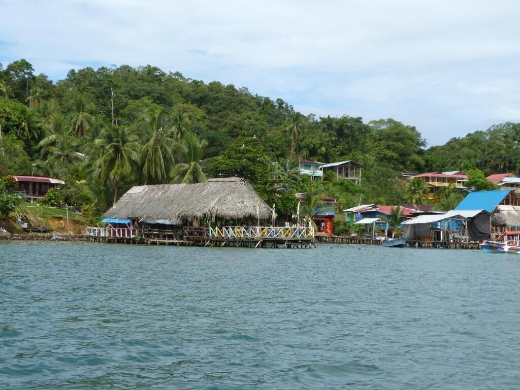 A coastal village with thatched-roof houses and wooden docks extending into the water.