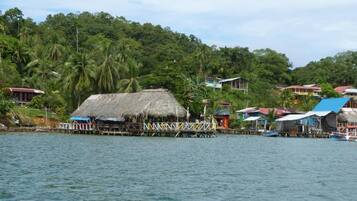 A coastal village with thatched-roof houses and wooden docks extending into the water.